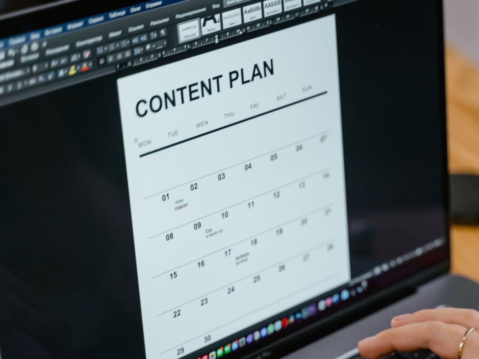 Mains rédigeant un plan de contenu éditorial sur un ordinateur portable